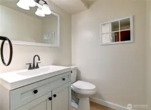 Lower-level bath w/ new vanity, sink, faucet, toilet, paint, millwork, lighting, flooring.