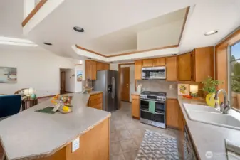 The kitchen features a gas range with double oven, stainless steel dishwasher, refrigerator and brand new garbage disposal. The neutral tile flooring and backsplash will meld with any decor. The door to the garage is seen just past the refrigerator.