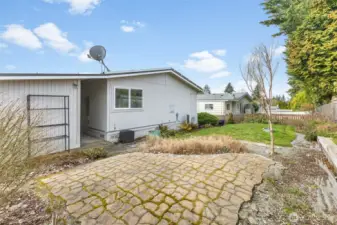 Back yard has pavers, small grass area & fencing