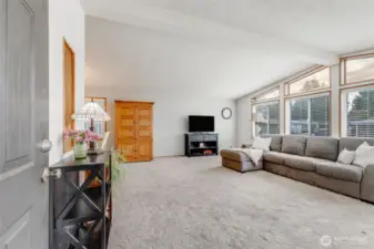 Welcome to the open living room with vaulted ceilings, updated windows, 2" faux wood blinds & lots of natural light