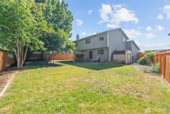 Fully fenced back yard with storage shed.