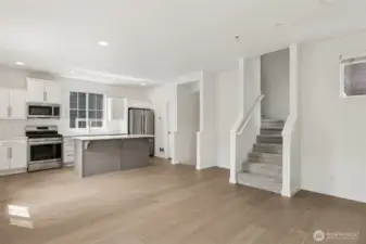 View from the living area toward the kitchen highlights the dual staircases that connect all three levels—creating an intuitive layout with effortless flow throughout the home.