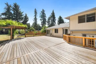 Spacious deck, wonderful outdoor living space, charming and well-established wisteria tree, decorative arbor, wrap-around stairs. This area is perfect for relaxing and entertaining, offering a beautiful and inviting outdoor environment.