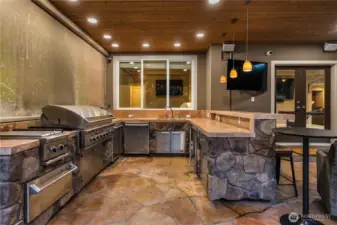 This covered outdoor kitchen lacks nothing but a party theme. Oversized gas barbeque, a grill, multiple warming trays, a keg AND a dishwasher. It's all here, no need to run upstairs.