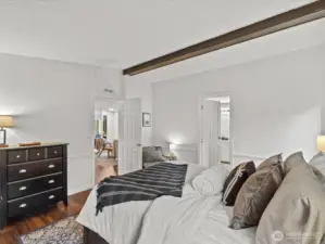 Primary bedroom with vaulted ceiling with wood beam.