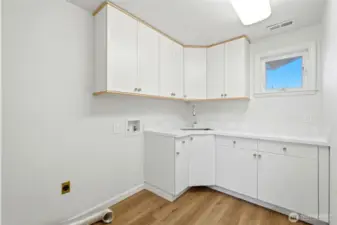 Utility room is conveniently located upstairs, and features quartz counters with corner sink and lots of cabinets.