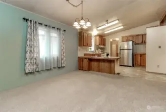 This view of the dining room faces the kitchen with the utility room on the other side of the kitchen and the back door.