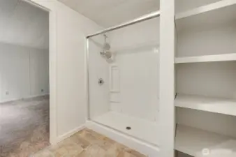 Primary bathroom provides a shower and storage shelves.
