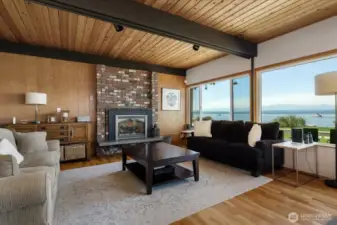 Large entertaining area with centrally located brick fireplace, exposed beams, and new expansive windows and doors to your deck.
