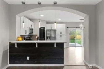 Breakfast bar with quart countertop, open concept kitchen looks out to living room and over dining room
