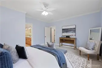 Main-floor generous primary suite with ceiling fan/light