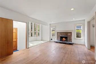 The spacious living room features original oak flooring and cozy a wood burning fireplace with Batchelder tile detail.