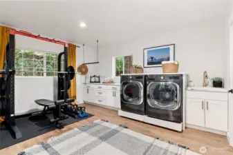 Grand laundry room with a wall of cabinets, utility sink and plenty of space for your private gym!