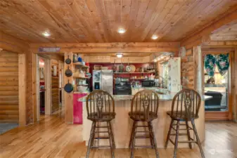 Kitchen with eating bar.  Down the hall is the powder room, a bedroom, large mudroom with laundry and door out to the back covered porch.