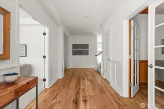 Impressive sense of arrival with wide entry and hallway, beautiful engineered hickory wood flooring, and wainscoting