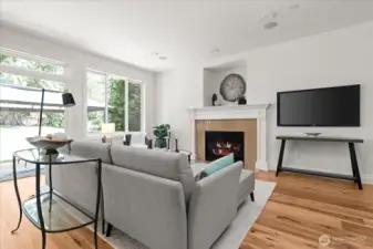 A great room with ambiance, offering natural light from oversized windows, warm hickory flooring, and gas fireplace