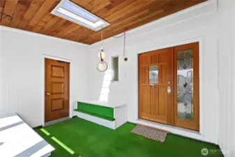 Front door to home with lead glass design window, opening sidelight with matching lead glass   Storm door entry  2 sitting benches  Wall to wall windows with blinds  Tongue & Groove ceiling with skylight  Entrance door to attached 2 car garage  Cat door