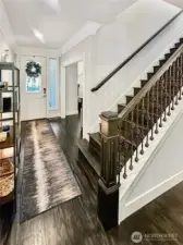 View of entry and stunning hardwood stairway with detailed wood and metal railing. Incredible trim and crown molding.