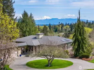 Beautiful territorial and mountain views from this 10-acre private estate. The circular drive is so convenient!  That's an Apple tree. There are flowering gardens to the left.