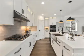Kitchen (alt. angle): Sleek cabinetry, modern hardware, and a gas cooktop pair seamlessly with under-cabinet lighting and ample pantry storage. This thoughtfully designed space makes meal prep effortless while staying connected to the heart of the home.  These photos are of the actual, staged home being sold at Foxmoore. However, all photos, renderings, site maps, and floorplans are for visualization purposes only. Plans, colors, building orientation, finishes, home outlook, and other details can and WILL vary.