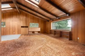 Great room features a vaulted ceiling, skylights, fireplace and large windows that let in ample natural light.