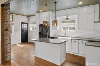 The kitchen island is located to perfectly to include your guest in the living room and dining room. Notice the original tongue and groove on the ceiling, giving so much character to the home.