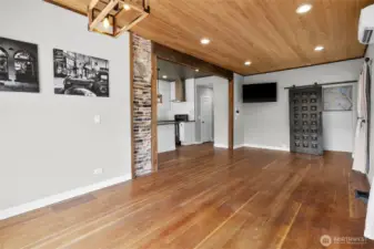 View from living area looking back to the dining room and kitchen on the left. The stylish barn door is your stairs to the upper primary bedroom with so much privacy.