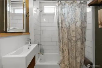 Main floor restroom with custom tile work, large bath tub and original wood accents.