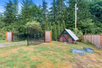 View of the Bigfoot gates paired with the playful miniature log cabin, showcasing the creative outbuildings and character that make this property truly unique.