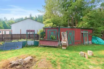 Cluster of rustic red outbuildings with green trim, including storage sheds and a playful “Boot Hill” sign. These structures add character while offering versatile space for projects, storage, or creative use.
