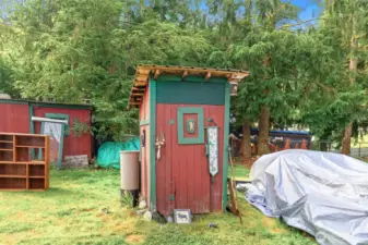 Charming small well house painted in red with green trim, accented by whimsical outdoor décor. A functional and distinctive feature that ties into the property’s rustic, handcrafted style.