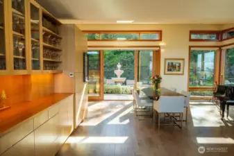 Dining area looking toward enclosed, mature garden. Built-in bar on left, maple engineered hardwood floors, clerestory windows.