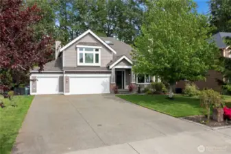 Immaculately maintained exterior with mature landscaping, a spacious three-car garage, and covered front porch create an inviting first impression.