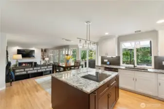 Chef’s dream kitchen with oversized island, glass pendant lighting, granite counters, and open sightlines to the dining and living spaces—ideal for entertaining.