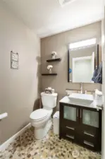 Main Floor Half Bath: Chic and modern powder room with custom vessel sink, designer vanity, and stone mosaic flooring—perfectly positioned for guest use on the main floor.