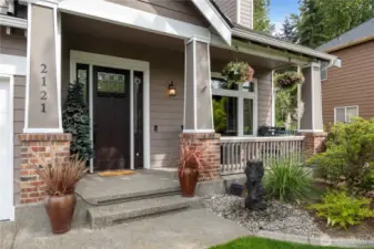 Front Porch – Inviting curb appeal with brick columns, planters, and hanging baskets.