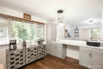 Pass-through counter to the dining room. Includes a tall grey pantry cabinet with 2 doors, 2 drawers, and double-door lower cabinets. Coffee bar not included.