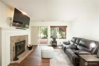 Cozy lower-level living room includes a wood fireplace with glass door enclosure (cleaned Fall 2024). Brick hearth and 5’ wide white wood mantle. Sliding glass door to backyard with built-in pet door (18”H x 10”W).