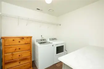 Functional laundry space with 2 upper wire shelves and lower grey cabinets with 2 drawers. Countertop is Formica with white and grey veining.