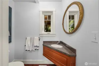 The main floor powder room features a carved custom cabinetry and a late antique mirror, brushed walls in a coastal blue.