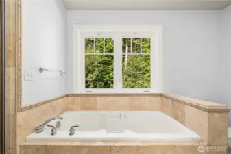 The primary bath offers travertine flooring, a bathing alcove with soaking tub, separate shower, and built-ins.