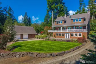 A great view showing the back of main house and the complementary style of the lower level separate guest quarters and detached garage and shop.