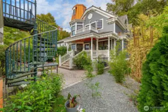 Rear of the home. Covered porch off the back with a deck off the primary above. Spiral staircase in the foreground leads to the Accessory unit above the garage.