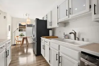 Kitchen with white cabinetry, newer SS dishwasher and refrigerator