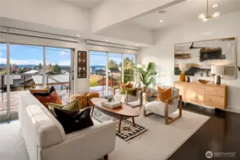 Sun-drenched living spaces open to the deck through walls of glass, capturing Olympic Mountain views beyond.
