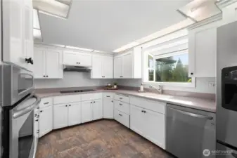 Alternate view of kitchen showcasing stainless steel appliances, flooded with natural light from garden window. Your pantry lies directly to the right of the refrigerator. All appliances stay with home.