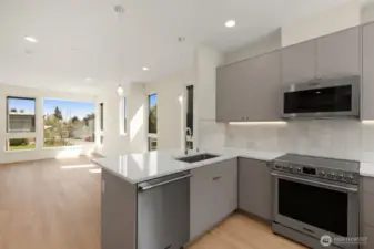 Photos of model home with similar finishes & floor plan. Close-up of kitchen features: tile backsplash, under-cabinet lighting, and polished countertops.