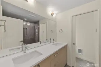 Photos of model home with similar finishes & floor plan. Full bath with double vanity, quartz counters, and elegant wall lighting.