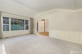 Formal living room is bright and sunny with large windows and raised ceilings.