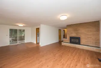 Open light filled living and dining room, gas fireplace, new luxury vinyl plank flooring over original hardwood floors.